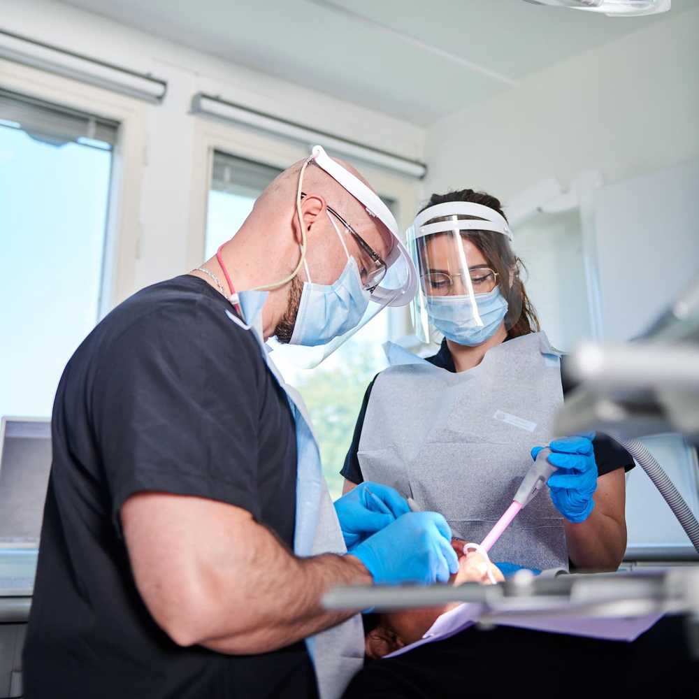 En tandläkare och en tandhygienist arbetar på en patient